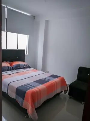 a bedroom with a bed and a chair at Amplio departamento completo cerca al aeropuerto in Lima