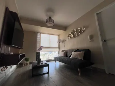 a living room with a black couch and a window at The Pool & City Spot - steps from Miraflores in Lima