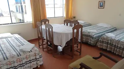 a room with four beds and a table and chairs at Hotel Perseo Inn in Barranca