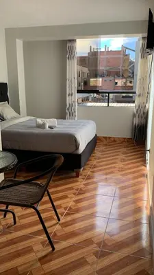 a bedroom with a bed and a chair and a large window at Hostal El Mariscal in Urubamba
