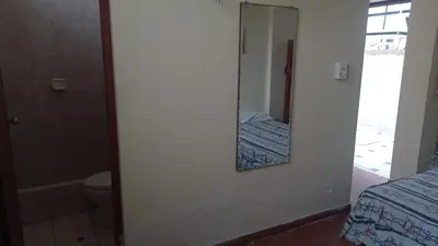 a bathroom with a mirror and a bed and a toilet at Hotel Perseo Inn in Barranca