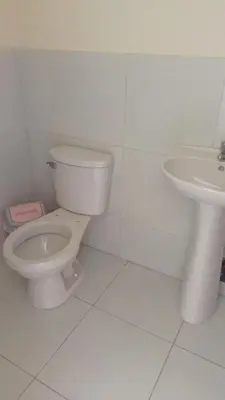 a white bathroom with a toilet and a sink at Hotel Perseo Inn in Barranca