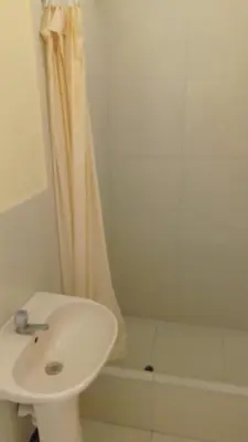 a white bathroom with a sink and a shower at Hotel Perseo Inn in Barranca