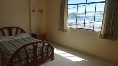 a bedroom with a bed and a window with a view of the beach at Hotel Perseo Inn in Barranca
