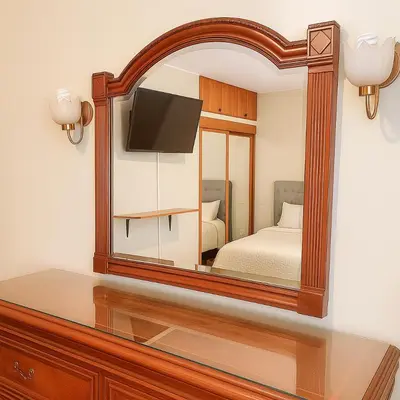 a mirror reflecting a bedroom with a bed and a tv at Bello departamento en el corazón de Miraflores in Lima