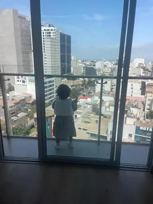 a little girl looking out of a window at a city at Departamento en Magdalena limite con San Isidro in Lima