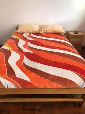 a bed with a colorful striped blanket on it at Taytacha House in Cusco
