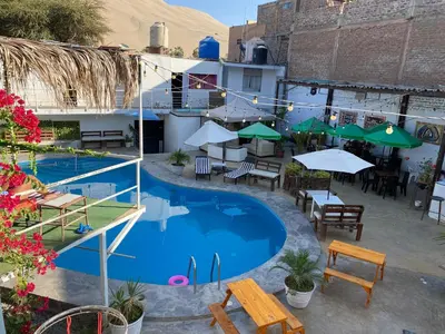 an overhead view of a pool with tables and umbrellas at Allawaska Hostel & Camping in Laguna Huacachina