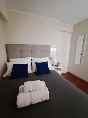 a bedroom with a large bed with blue and white pillows at Room in shared apartment - Shared Bathroom 402 in Lima