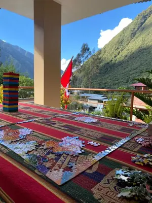 a table with carpets on a balcony with mountains at Eco Lodge Elegant Qollpawasi in Colcapampa