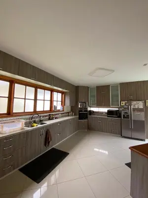 a large kitchen with wooden cabinets and stainless steel appliances at Casa Vaí Cieneguilla with a pool in Cieneguilla