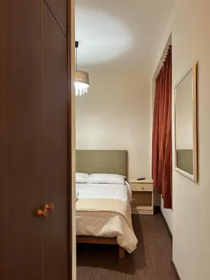 a small bedroom with a bed and a mirror at Kontiki Miraflores in Lima