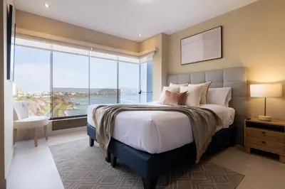 a bedroom with a large bed with a large window at ALU Apartments - Ocean View at Larcomar Miraflores Next to JW Marriott in Lima