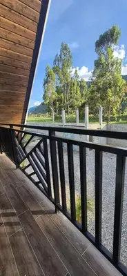 a balcony with a view of a field and trees at Prana Cabins Oxapampa in Oxapampa