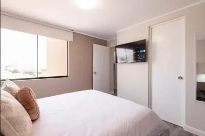 a bedroom with a white bed with a flat screen tv at DivarAparts#1 in Lima