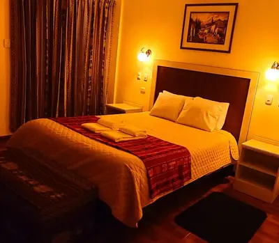 a bedroom with a large bed with white sheets and pillows at Hotel Casa Suite Inka in Ollantaytambo