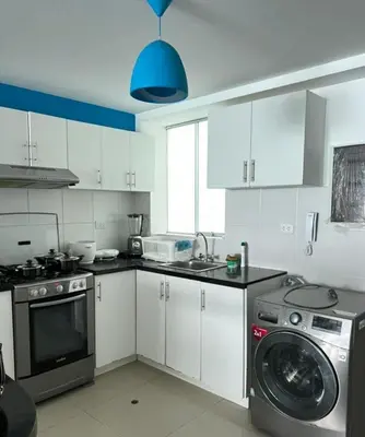 a kitchen with white cabinets and a washing machine at Beautiful apartment with an ocean view in San Bartolo