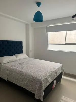 a bedroom with a bed with a blue headboard and a window at Beautiful apartment with an ocean view in San Bartolo