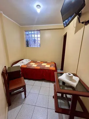 a bedroom with a bed and a table and a tv at Hs San Cristobal in Ayacucho