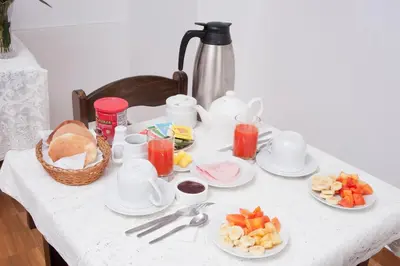 a table with plates of food and a basket of fruit at Carmen's House in Cusco