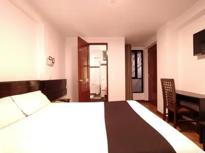 a bedroom with a bed and a table and a desk at Illas Inn in Cusco