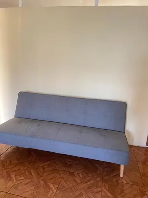 a blue couch sitting on a wooden floor in a room at Departamento amplio y cómodo a 15 minutos del aeropuerto in Lima
