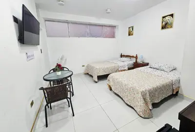 a room with two beds and a table and a tv at Familiar Premium Twin Chanchamayo in La Merced