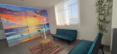 a living room with a blue couch and a painting at SKY HOUSE con vista al mar in Chincha Baja