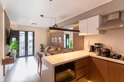 a kitchen with white cabinets and a living room at Brand-new designer apt - Pool in Miraflores in Lima