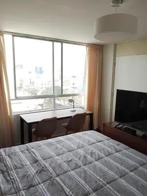 a bedroom with a bed and a desk and a large window at Miraflores, Lima, habitación independiente in San Antonio