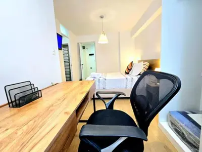 a chair in a room with a desk and a bed at Suite Ocean View con WiFi San Miguel 1502 in Lima