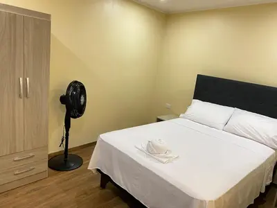 a bedroom with a white bed with a fan at Brisa Dorada - Luxury Apartment in Los Olivos in Lima