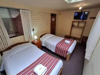 a hotel room with two beds and a television at Andean Dreams 1 in Cusco