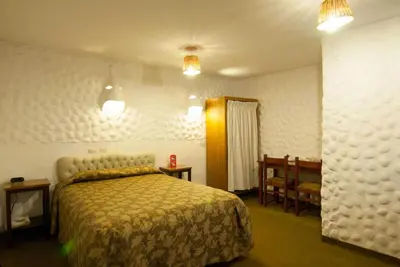 a bedroom with a bed and two tables and chairs at Hotel WhiteHouse in Cusco