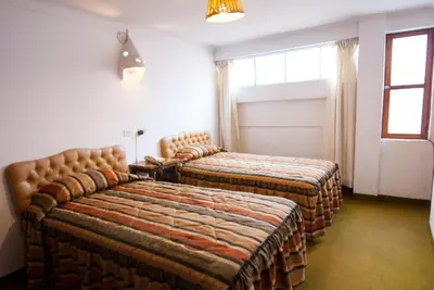 a hotel room with two beds and a window at Hotel WhiteHouse in Cusco