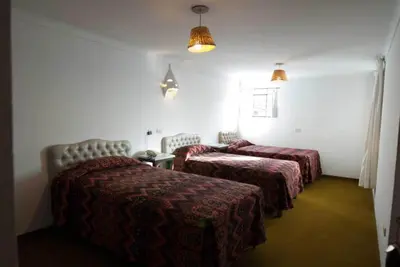 a hotel room with two beds and two chairs at Hotel WhiteHouse in Cusco