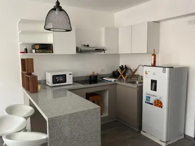 a kitchen with a white refrigerator and white cabinets at Apartament Qosco in Cusco