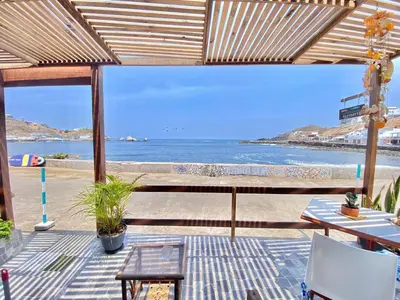 a patio with a view of a beach with a bench at BAHIA SUR HOUSE CASA a MAR SAN BARTOLO in San Bartolo