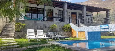 a house with chairs next to a swimming pool at Nice country house with pool and beautiful view in Huarochirí