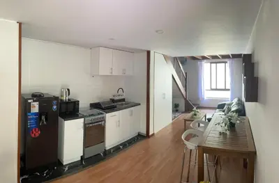 a kitchen with a refrigerator and a table in a room at SAELUMA Suite Apart in Lima