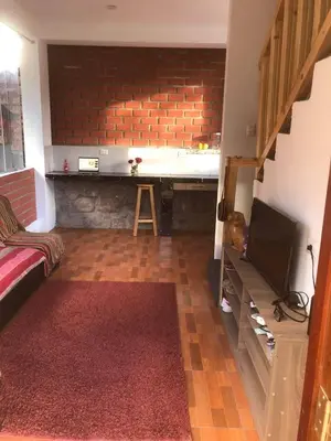 a living room with a television and a brick wall at Casa de Marguito in Urubamba