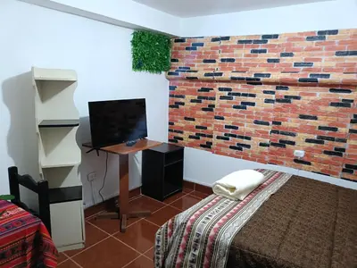 a bedroom with a brick wall and a desk with a television at 7 Borreguitos GUESTHOUSE in Cusco