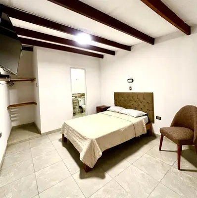 a bedroom with a bed and a chair at QPÑ Hoteles - Hacienda Nieve Nieve in Balconcillo de Aviyay