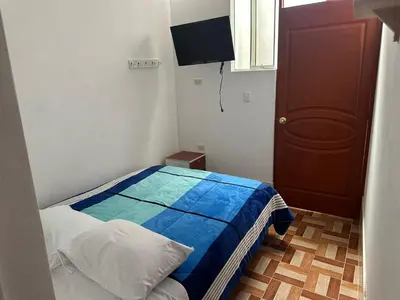 a small bedroom with a bed and a television at Hospedaje MARY in Quinua