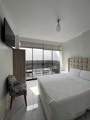 a bedroom with a bed and a chair and a large window at Nayarak Paracas in Paracas