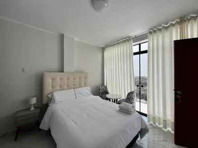 a bedroom with a white bed and a large window at Nayarak Paracas in Paracas