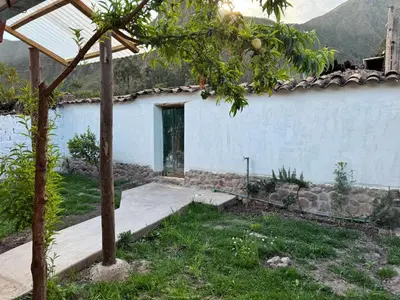 a white building with a door in a yard at Casa Muyuna in Calca