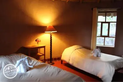 a bedroom with two beds and a lamp and a window at Hanaq Pacha Wasi in Calca
