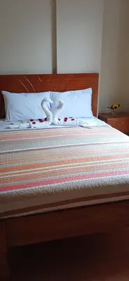 a bed with a wooden head board with flowers on it at Haylli Café Oro Hotel in Santa Teresa