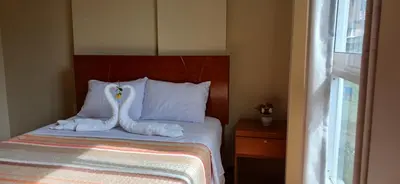 a bedroom with a bed with white sheets and pillows at Haylli Café Oro Hotel in Santa Teresa